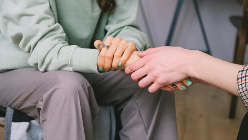 Two people holding hands for comfort while grieving