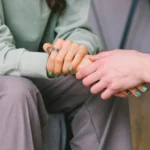 Two people holding hands for comfort while grieving