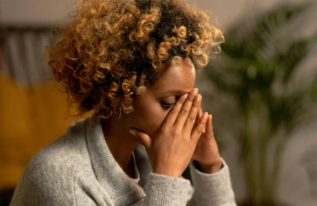 A woman with her hands over her face, overwhelmed by grief