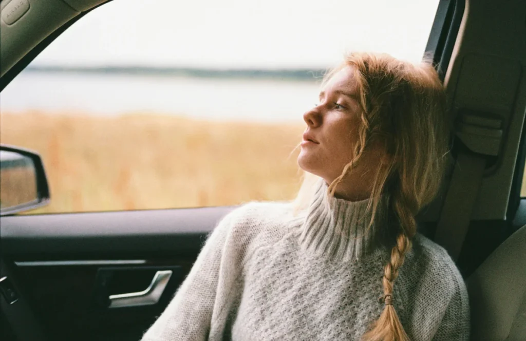 A woman sitting in a car looking out the window, recovering from a car accident