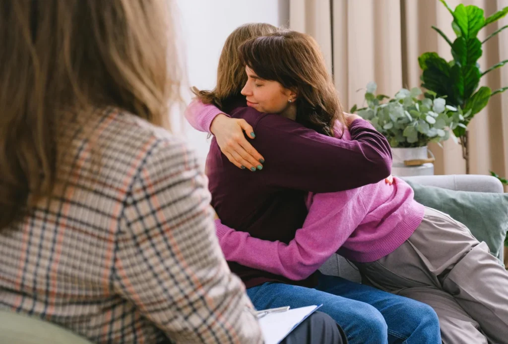 A South Asian mother and adult daughter hugging after a difficult conversation
