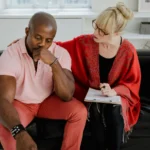 A couple sitting apart on a couch after an argument