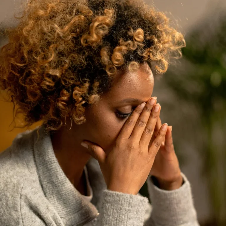 A woman with her hands over her face, overwhelmed after a traumatic event