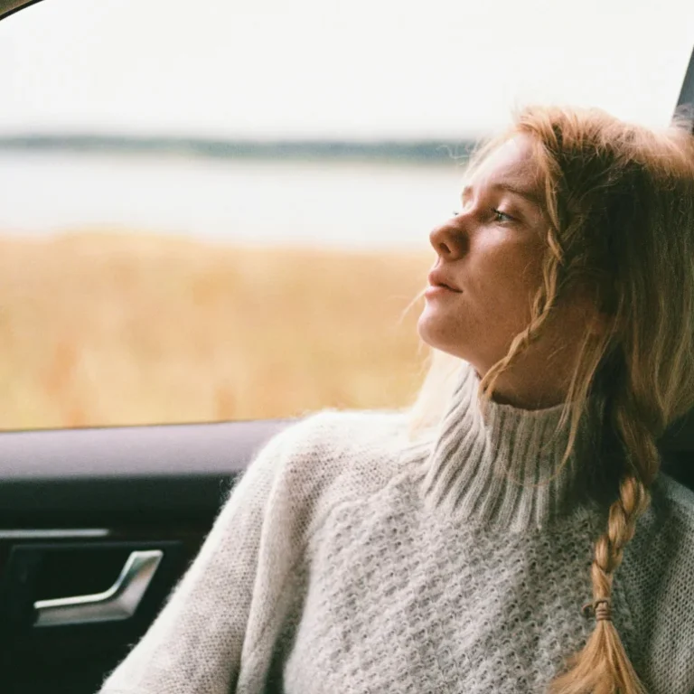 A woman sitting in a car looking out the window, recovering from a car accident